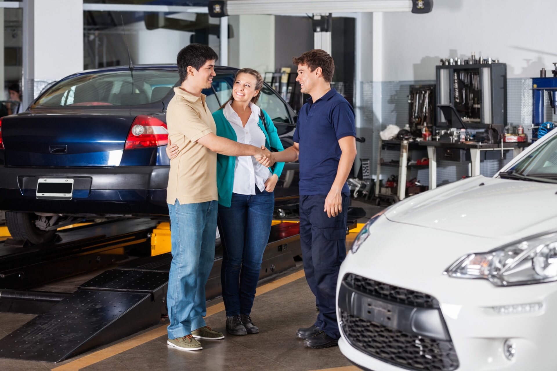 mechanic shaking hand with couple at auto repair shop