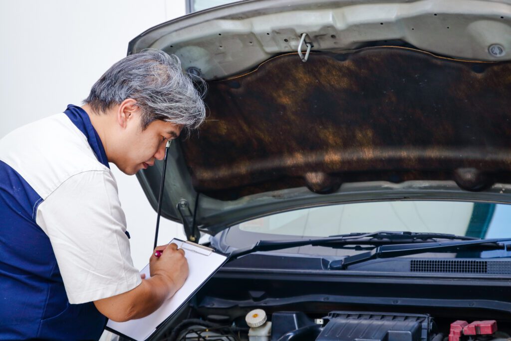 A car mechanic is recording a checklist of a car's condition